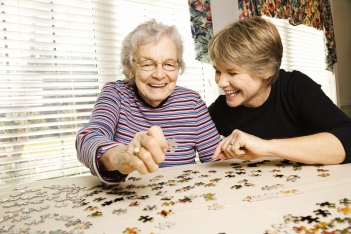 old woman making a puzzle complete with the help of young woman