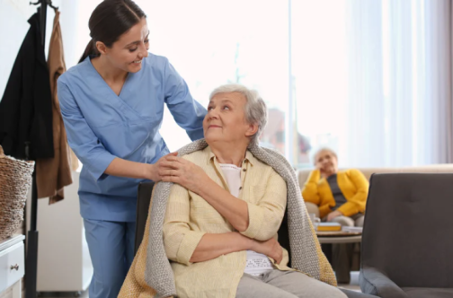 Hospice_nurse_putting_a_blanket_on_patient.png